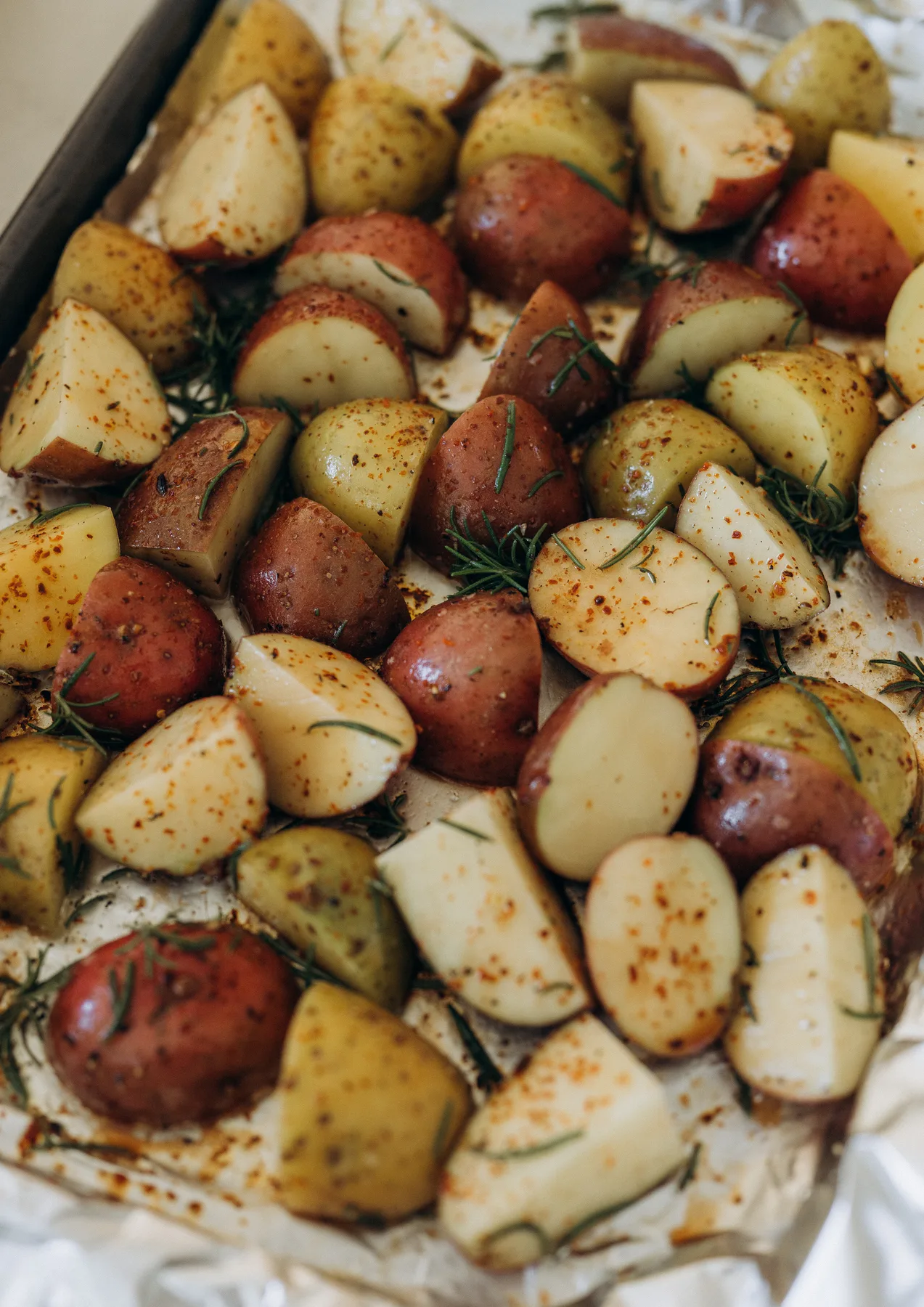 A tray of roasted potatoes with herbs.